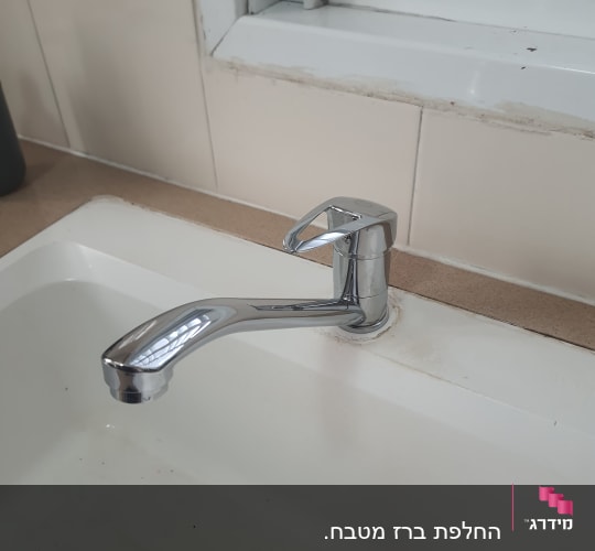 ברז כרום מותקן בכיור לבן עם ניקוז מתכת